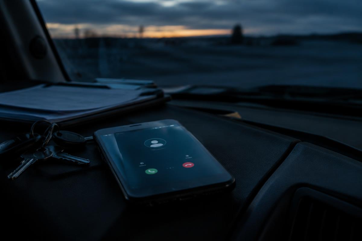 Phone lit up with a missed call on a truck dashboard at dusk